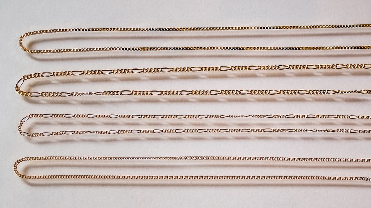 Four thin 18k gold chains laid straight: venetian box, figaro and two curb chains