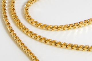 Gold Franco chain coiled on a white background, showing the dense four-sided weave