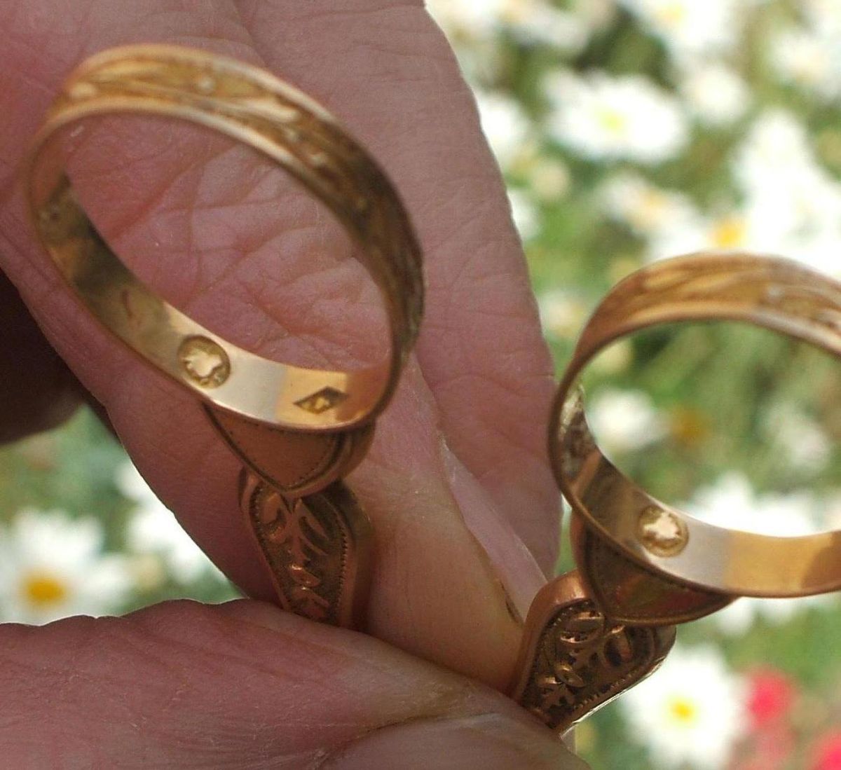 Two gold rings held in fingers, each showing a small French eagle-head hallmark