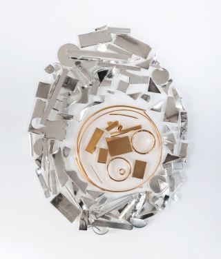 Scrap gold offcuts and wire arranged in a circle, surrounded by scrap sterling silver pieces, on white
